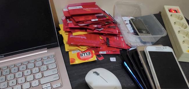 The desk of a buzzer, with dozens of phone cards and seven mobile phones / Wijayanto