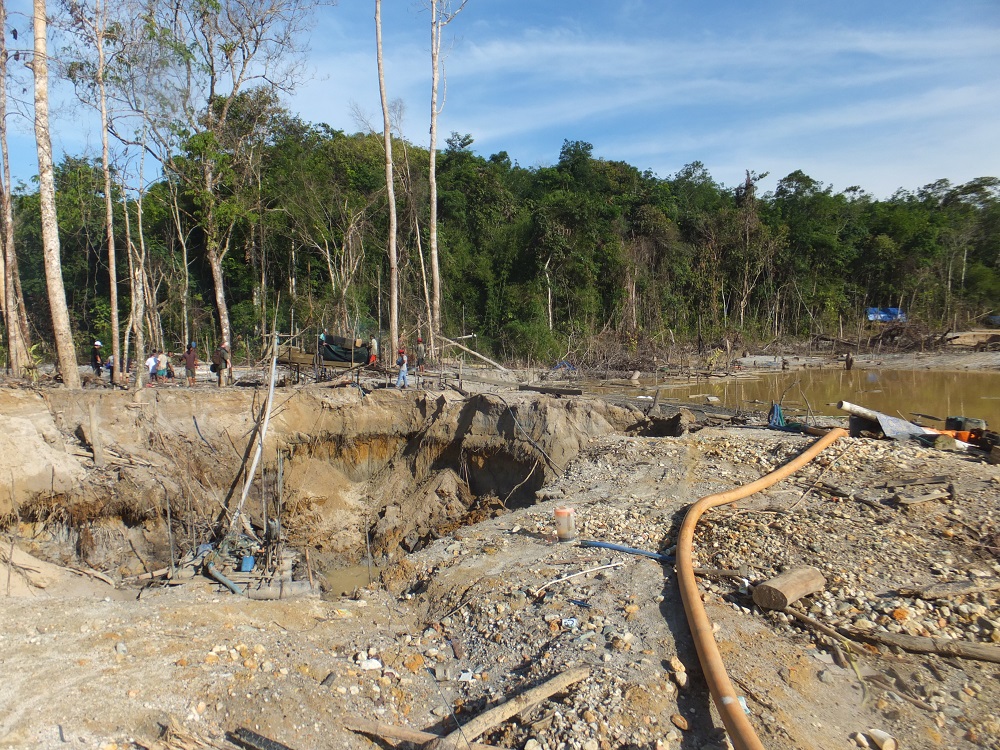 A base of community miners. People's mining (or tambang rakyat) are not clearly defined in law and pit such miners against big corporations. (Kuntala Lahiri-Dutt) A mining base, with a pipe running across the foreground and some wooden structures.